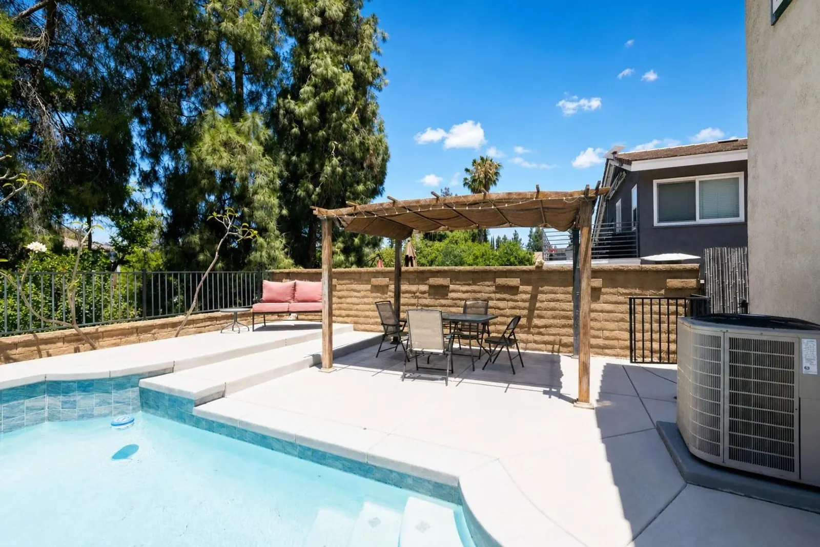 Backyard pool under a blue sky with clouds