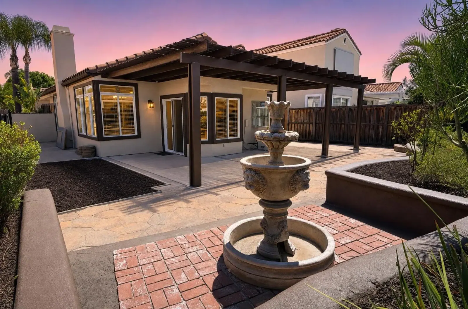 Backyard with a fountain and pergola at twilight