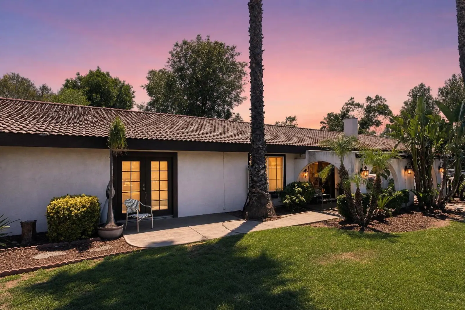 Single-story ranch home at twilight with the doors lit