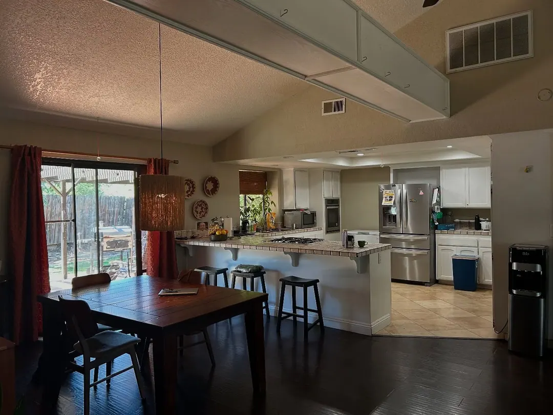 Original iPhone photo of a dark dining room and kitchen under a vaulted ceiling